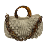 Hand-crocheted Paloma handbag in a soft nude-beige tone with textured stitching, featuring a sculptural resin top handle and a coordinating chain strap.