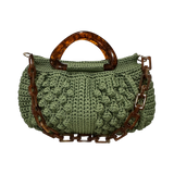 Hand-crocheted Paloma handbag in a soft sage green tone with textured stitching, featuring a sculptural resin top handle and a coordinating chain strap.