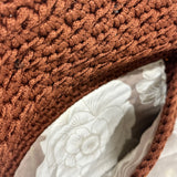 Interior view of the Polly Clutch showcasing textured cinnamon-brown crochet craftsmanship and a soft floral lining in layered ivory and warm neutral tones with secure magnetic closure detail.