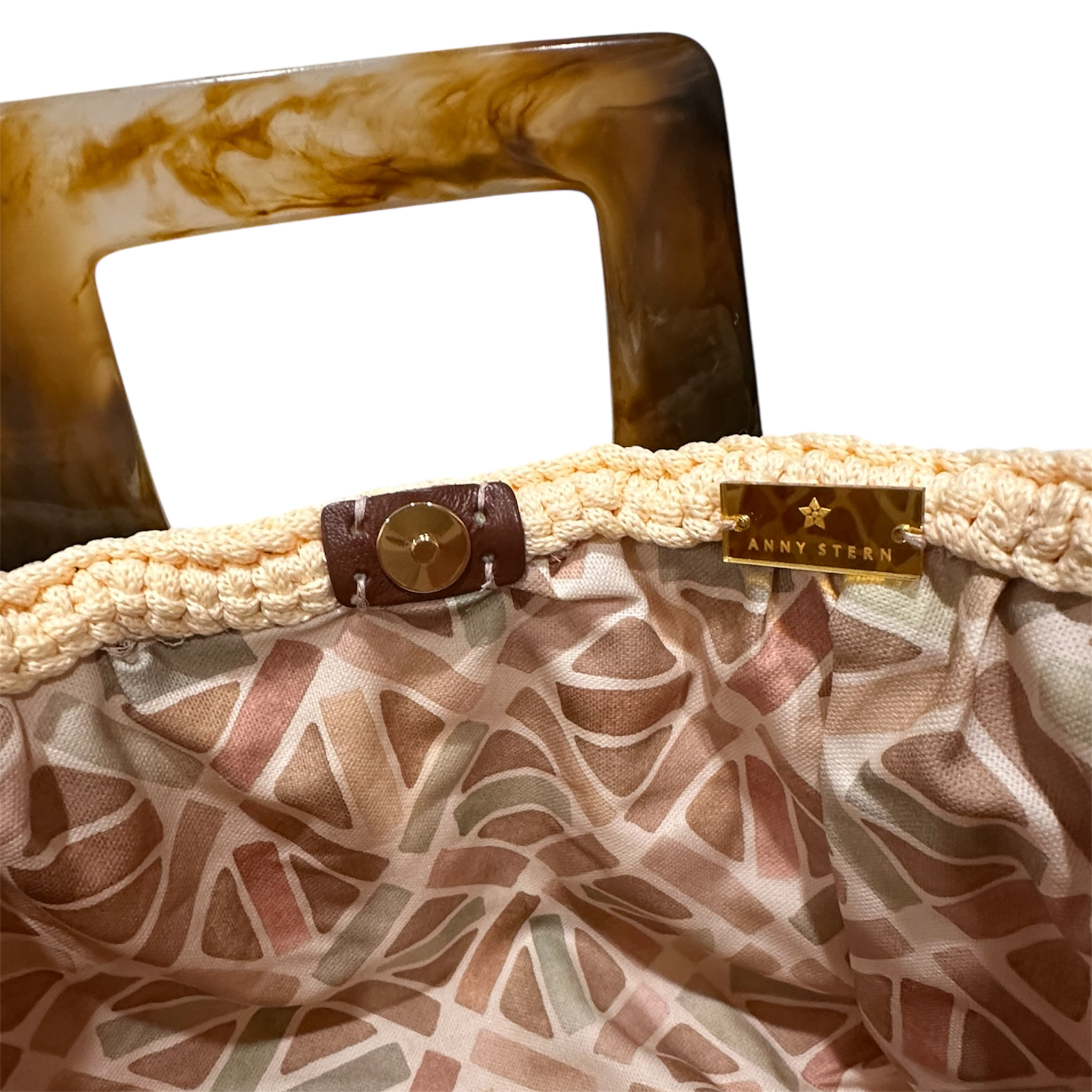 Interior view of the Paloma handbag · Lumen Dune, featuring a geometric mosaic lining in soft neutral tones, framed by the textured crochet structure and refined resin handle details.