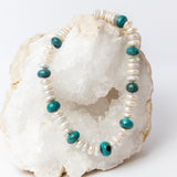 Laguna Bianca Necklace featuring luminous white freshwater coin pearls, center-drilled for a distinctive stacked, rondelle-like appearance, accented with polished blue-green turquoise stones and finished with a silver clasp.