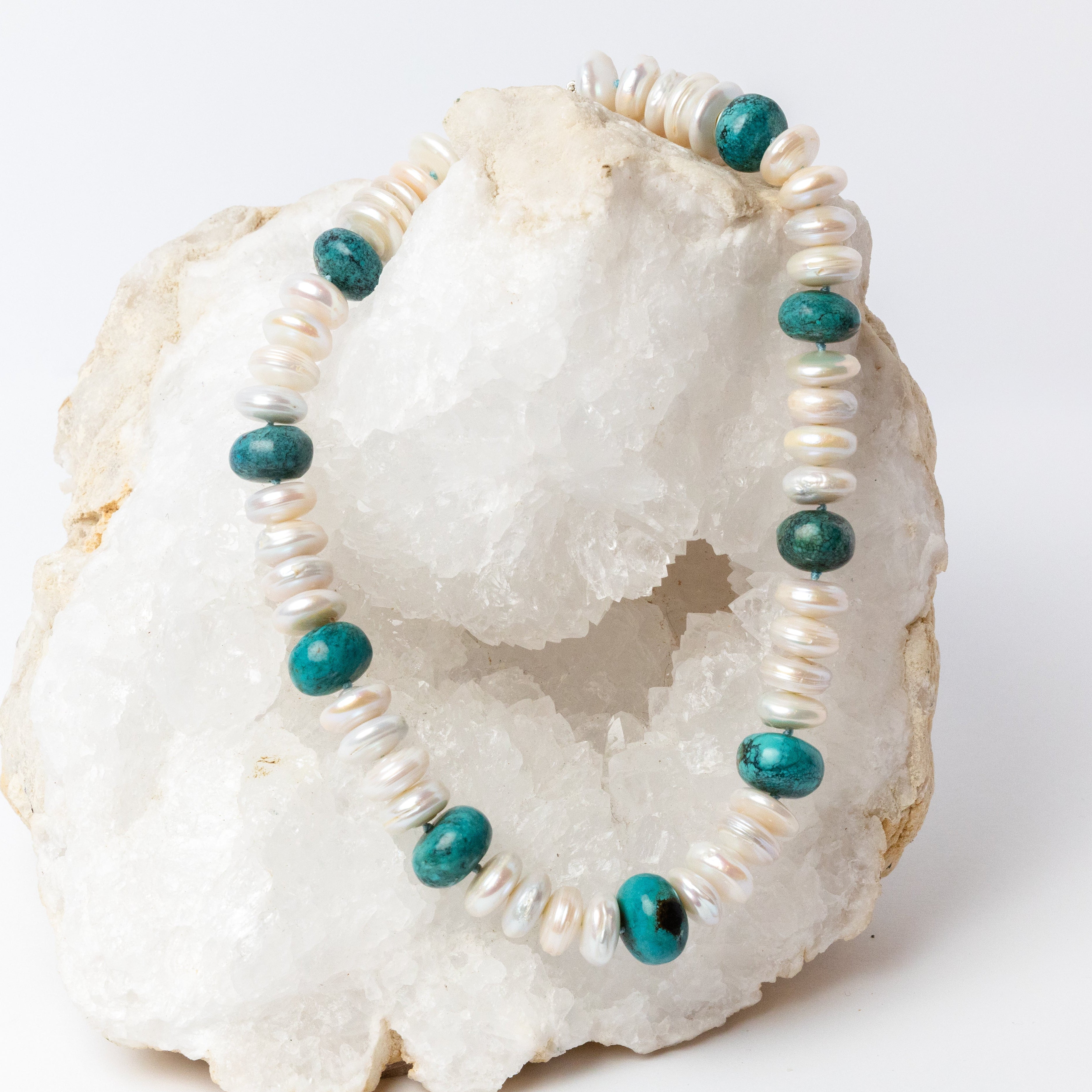 Laguna Bianca Necklace featuring luminous white freshwater coin pearls, center-drilled for a distinctive stacked, rondelle-like appearance, accented with polished blue-green turquoise stones and finished with a silver clasp.