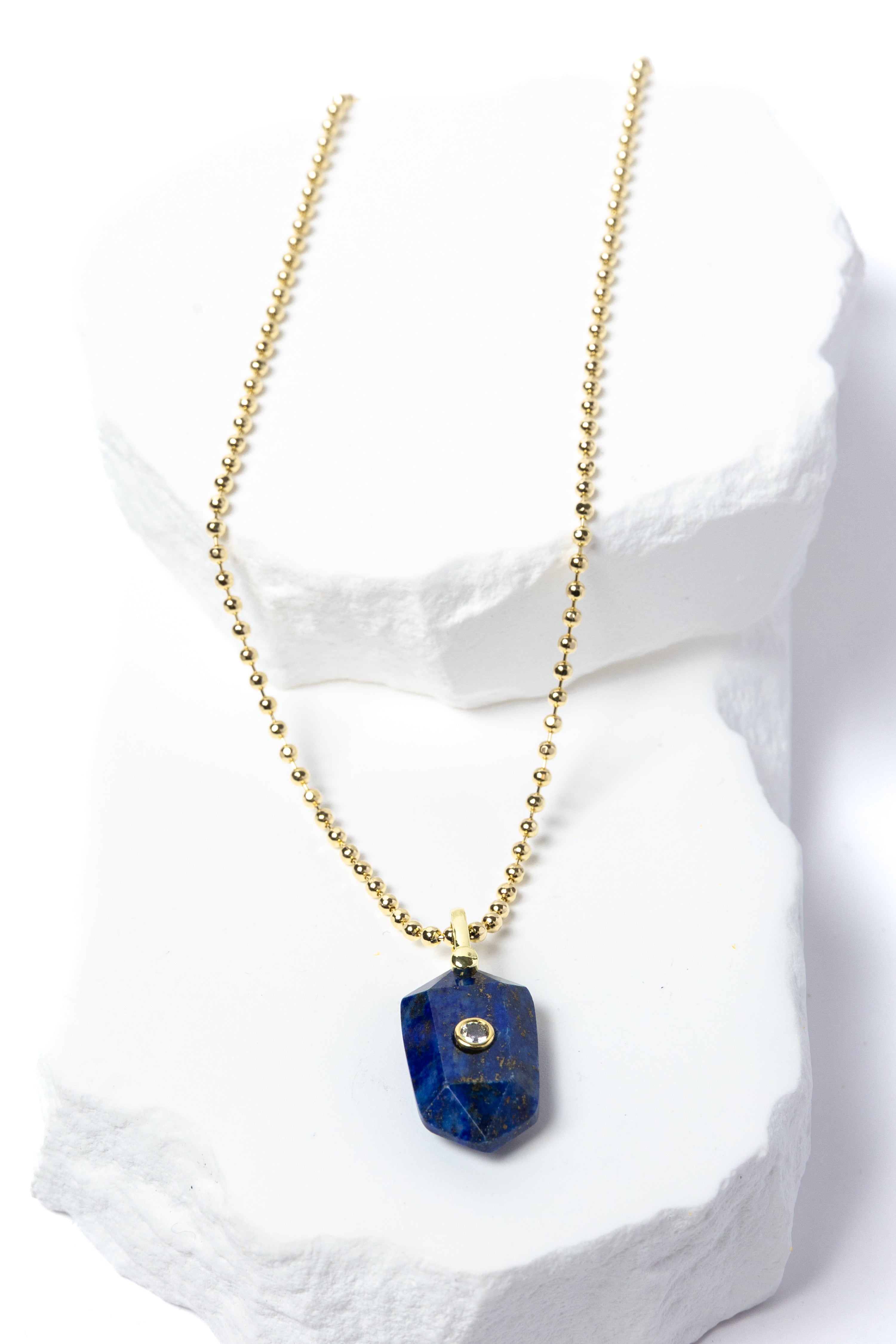 Natural Lapis Lazuli Gem Charm Necklace featuring a faceted royal-blue gemstone pendant with natural golden inclusions, cubic zirconia accent, and gold-plated beaded chain 