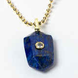 Close-up of a natural Lapis Lazuli pendant showcasing deep royal-blue tones, natural golden inclusions, faceted geometric shape, cubic zirconia detail, and gold-plated setting.