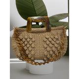 Hand-crocheted Paloma handbag in a warm camel beige tone with dimensional textured stitching, featuring a marbled amber resin top handle and a coordinating chain strap.
