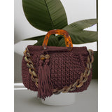 Hand-crocheted Giselle handbag in a deep bordeaux tone with dimensional vertical textured stitching, featuring marbled amber resin round handles, a coordinating chain strap, and tassel accents.
