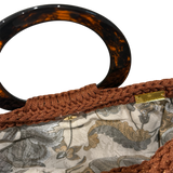 Interior of the copper Monique handbag featuring a botanical lining in beige, gray, brown, and warm neutral tones with magnetic closure.