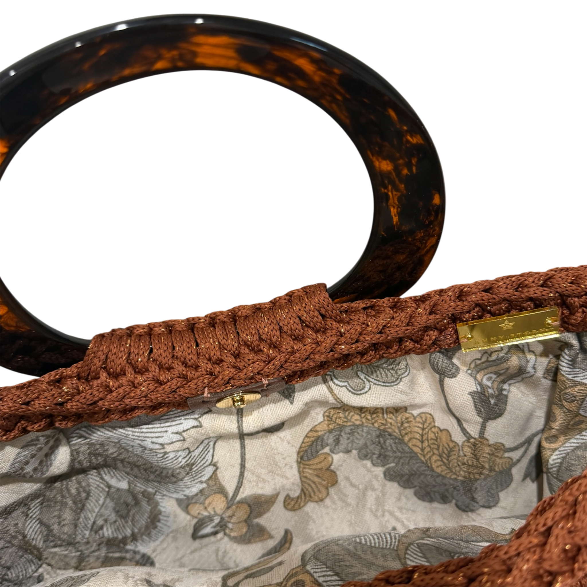 Interior of the copper Monique handbag featuring a botanical lining in beige, gray, brown, and warm neutral tones with magnetic closure.