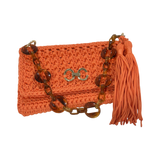Close-up of crochet texture, gold-tone detail, and tassel on orange unique Polly clutch