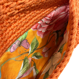 Interior of orange crochet clutch with floral lining and secure closure