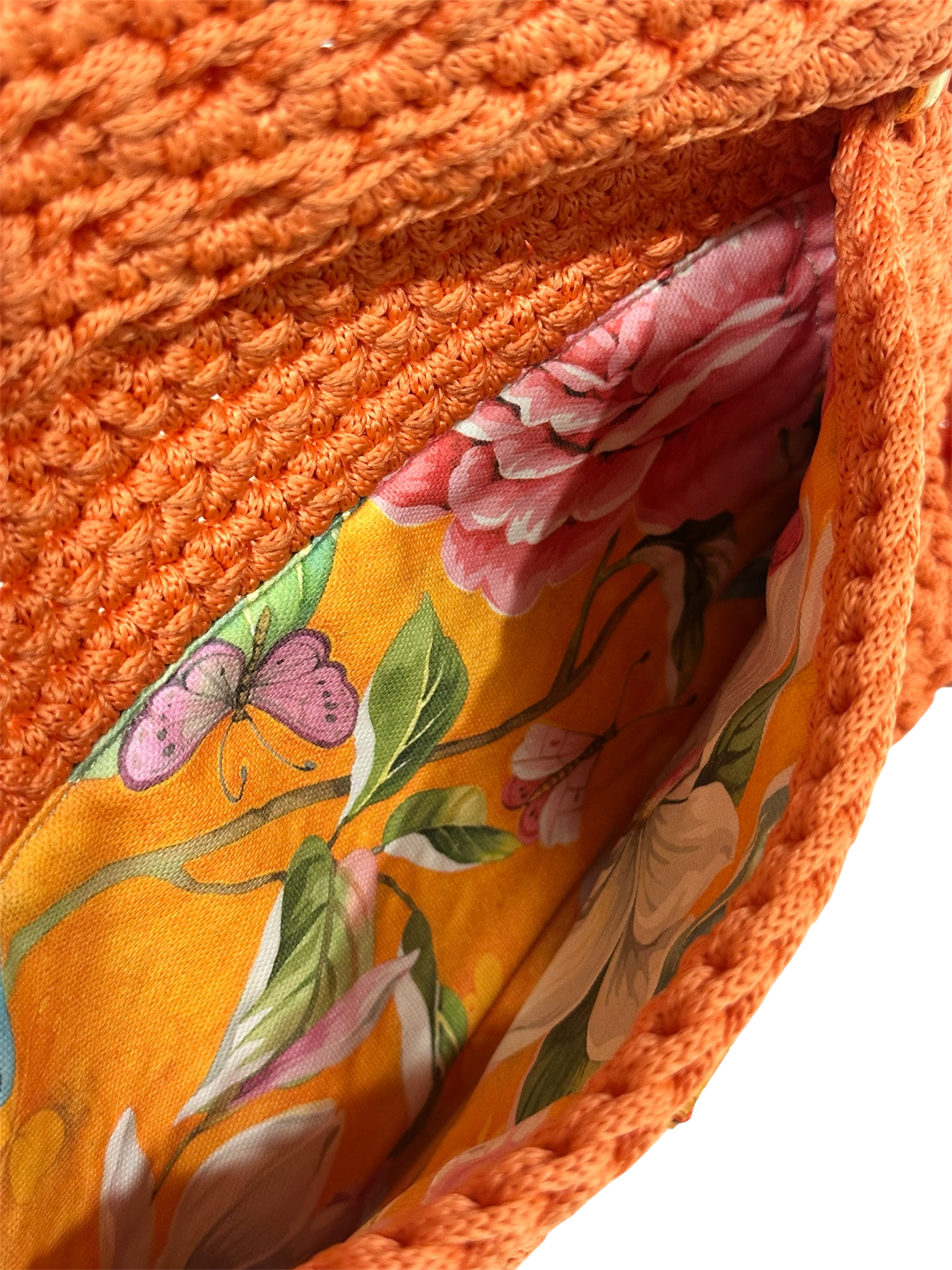 Interior of orange crochet clutch with floral lining and secure closure