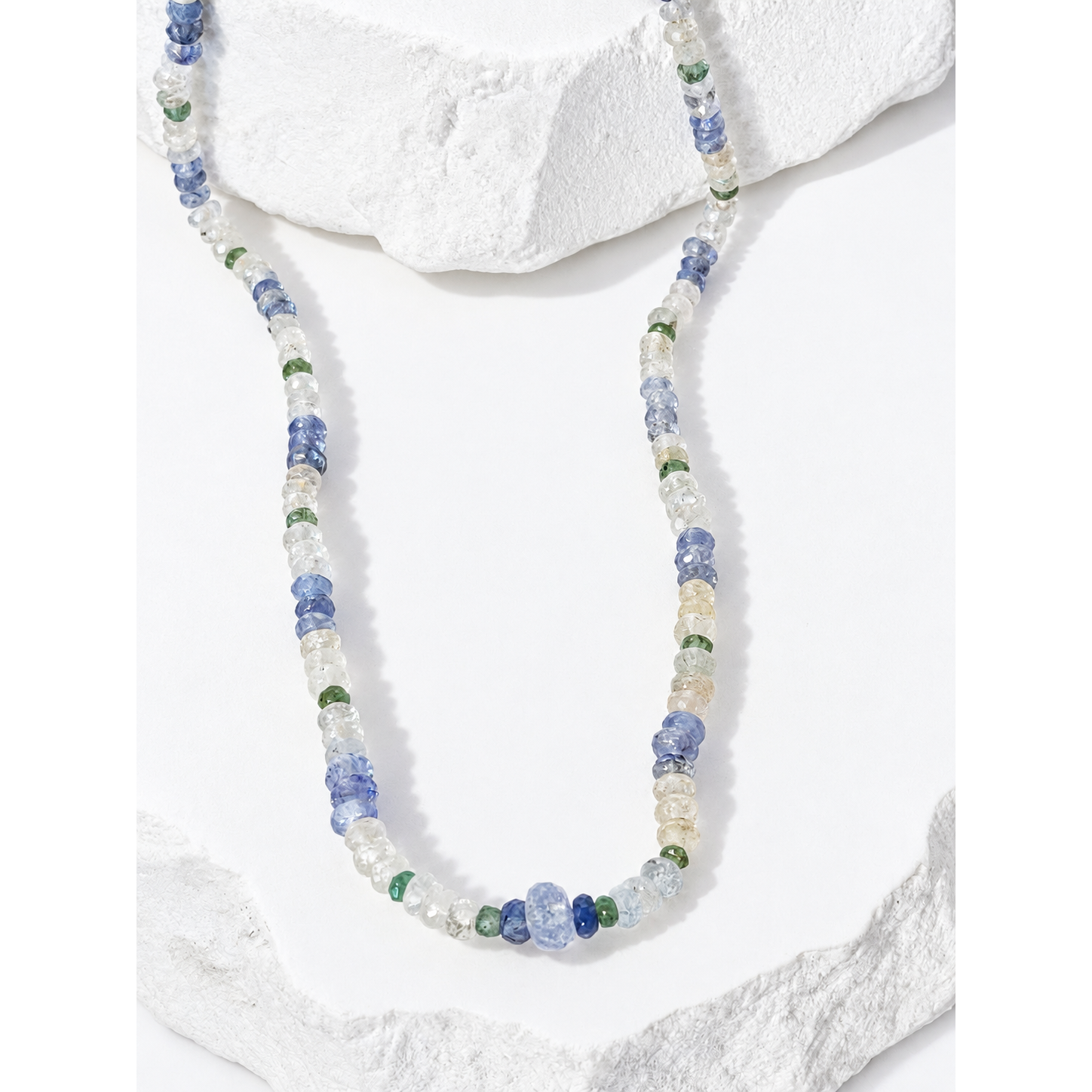 Close-up of natural multicolor sapphires and emeralds showcasing the necklace’s delicate variations of pale blue, soft green and luminous neutral tones.