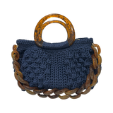 Hand-crocheted Paloma handbag in a deep sapphire blue tone with dimensional textured stitching, featuring a marbled resin top handle and a coordinating chain strap.