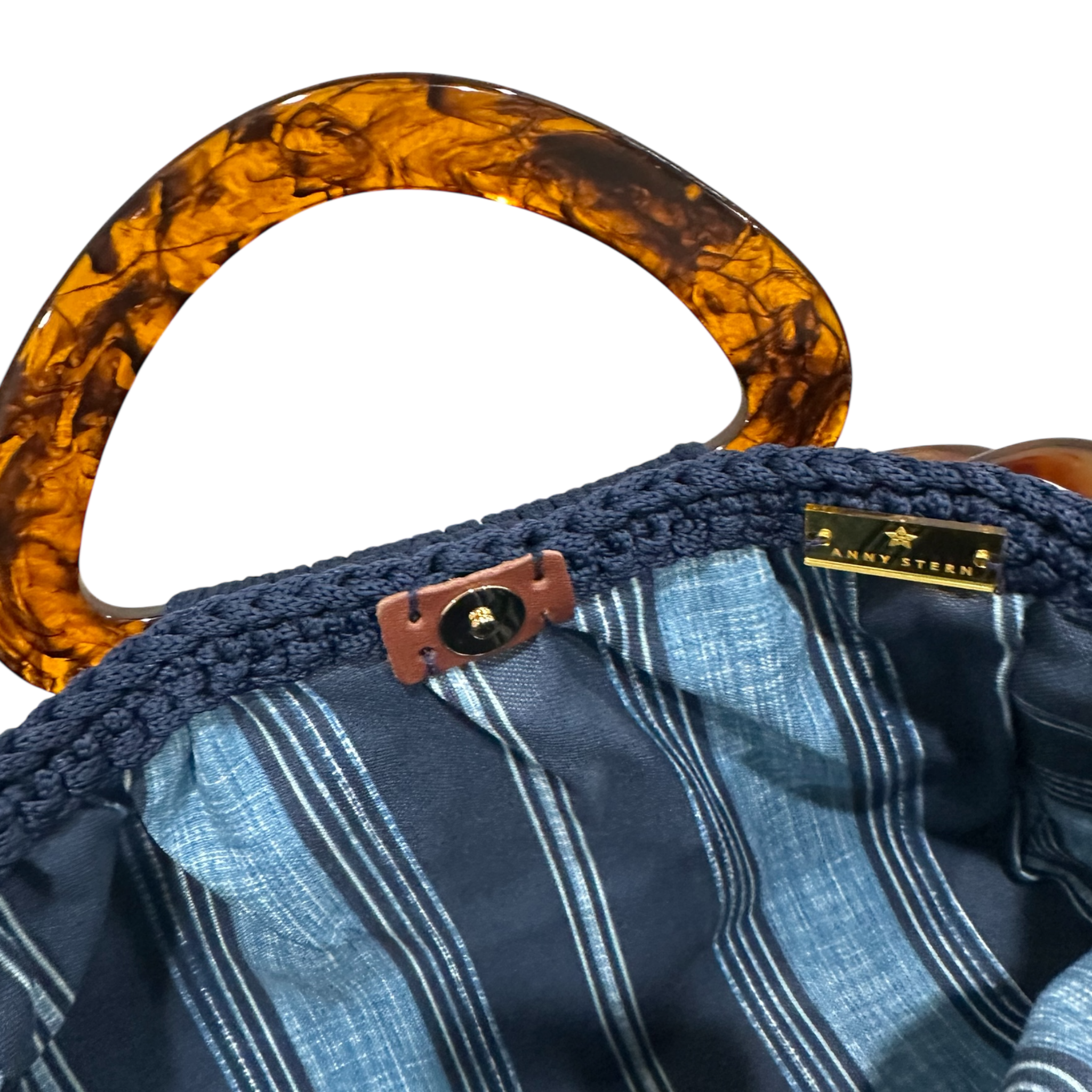 Interior view of the Paloma handbag · Deep Harbor, showing a striped fabric lining in tonal blue hues, framed by the structured crochet body and finished with refined resin handle details.