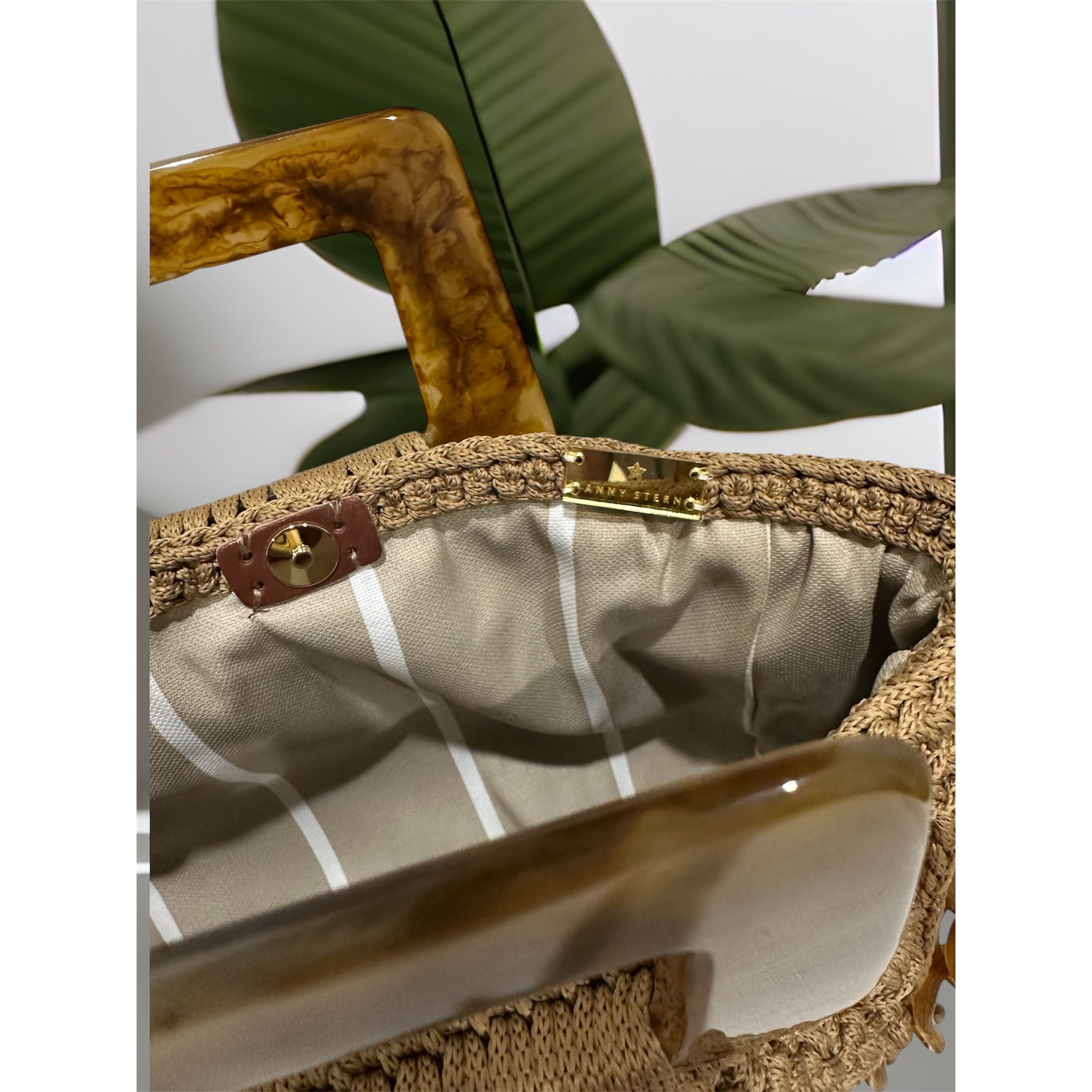 Interior view of the Paloma handbag · Champagne Mirage, featuring a striped lining in soft beige and white tones, framed by the structured crochet body and finished with refined resin handle details.
