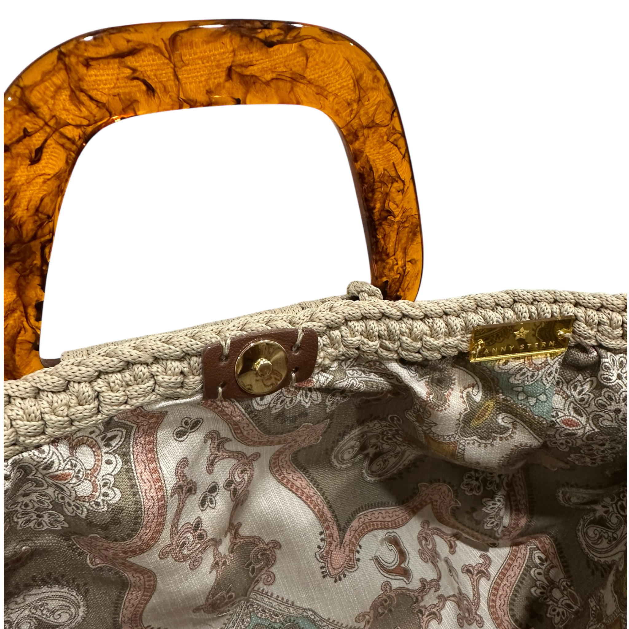 Interior view of the Giselle handbag, revealing an ornate patterned lining inspired by the Belle Époque era, framed by the softly structured crochet silhouette and finished with refined resin handle details.  