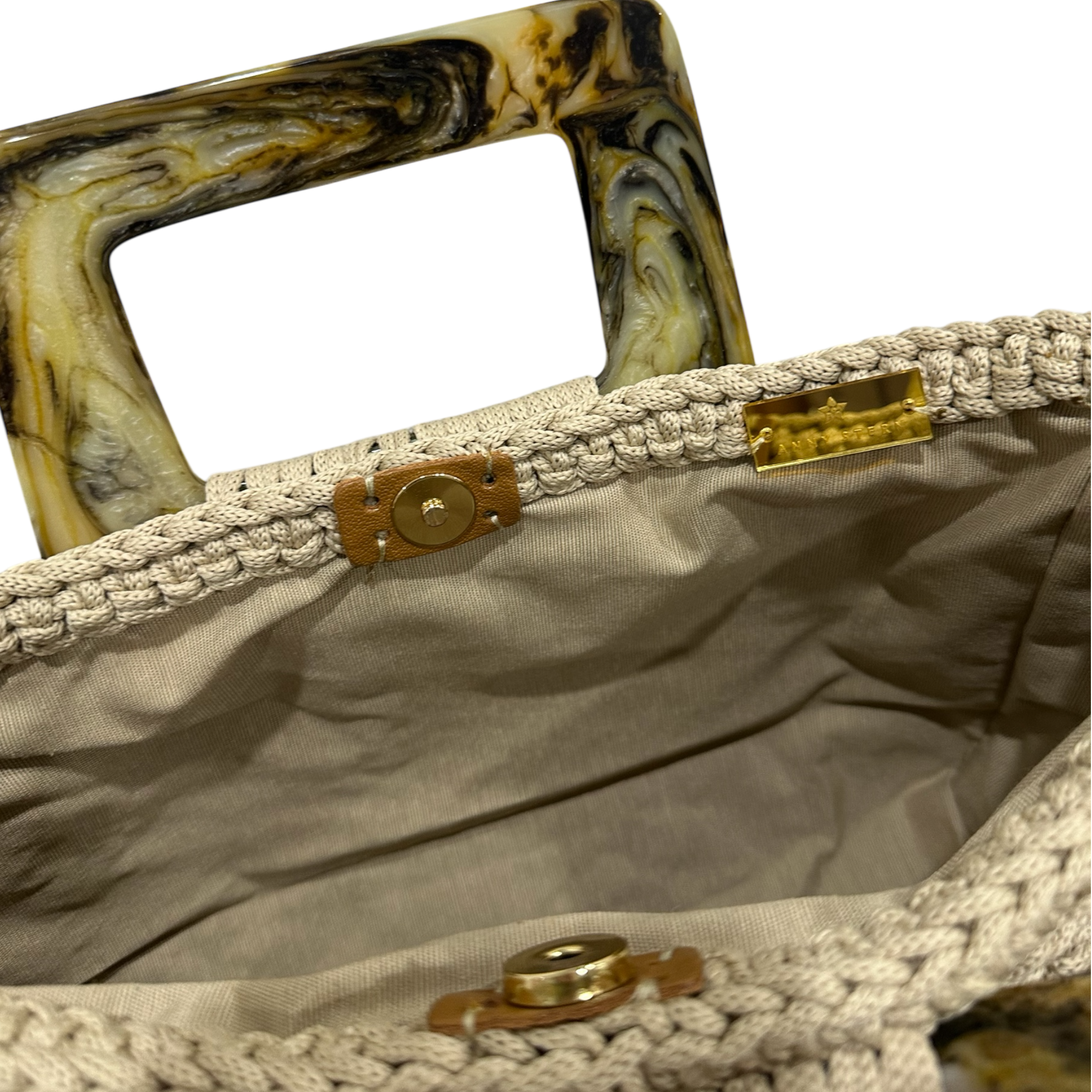 Interior view of the Paloma handbag · Stone Veil, showing a solid beige lining, framed by the softly structured crochet body and finished with refined resin handle details.