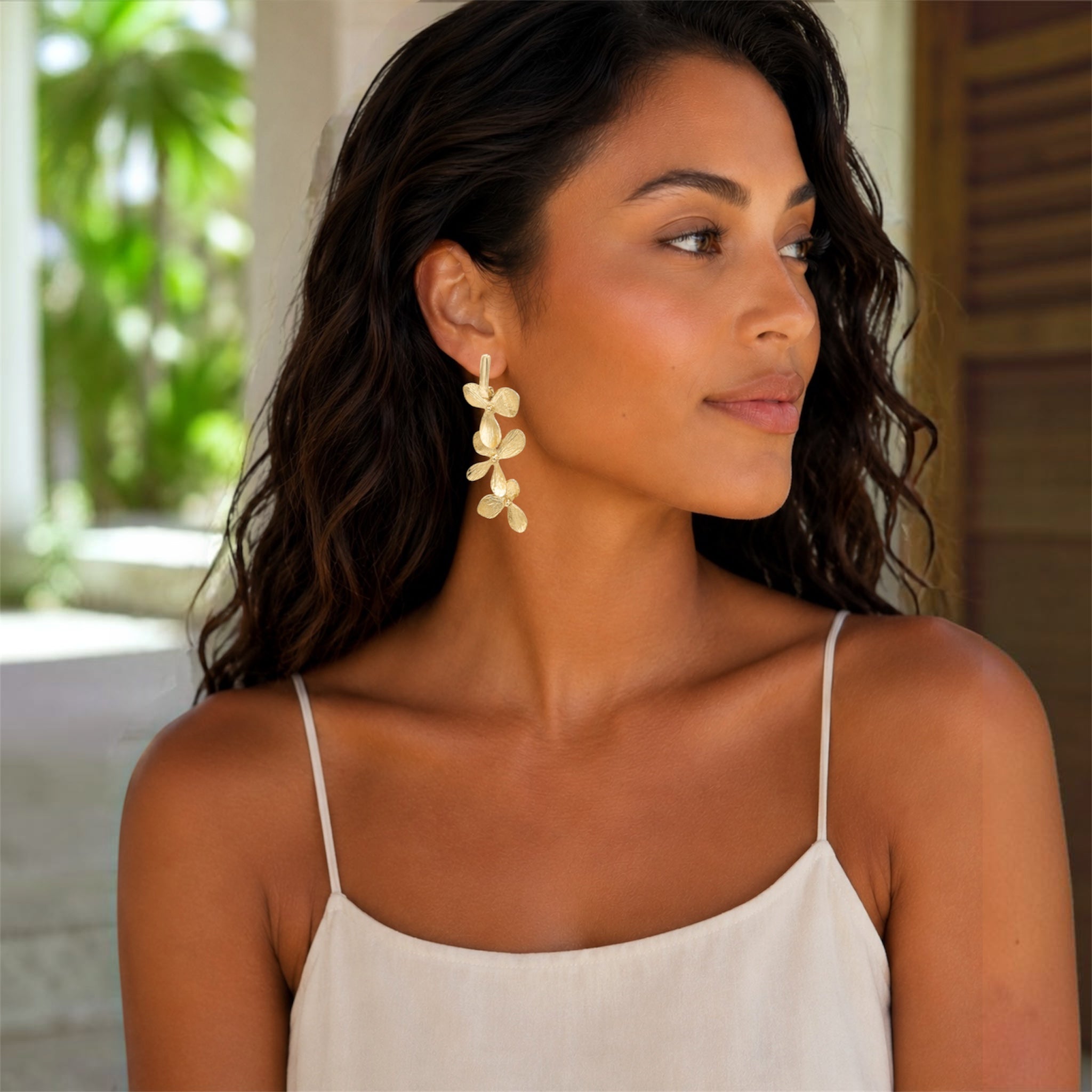 Model wearing Orchid Cascade gold-plated statement earrings with three sculptural orchid flowers and a 2.5-inch drop.