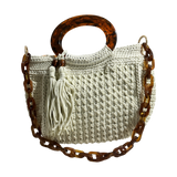 Off-white hand-crocheted Giselle handbag with tortoiseshell resin handle, coordinating chain strap, and tassel with tone-on-tone bead accents, featuring a neutral foliage lining.