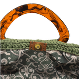 Interior of olive green Paloma handbag with deep green ornamental patterned lining and magnetic closure.