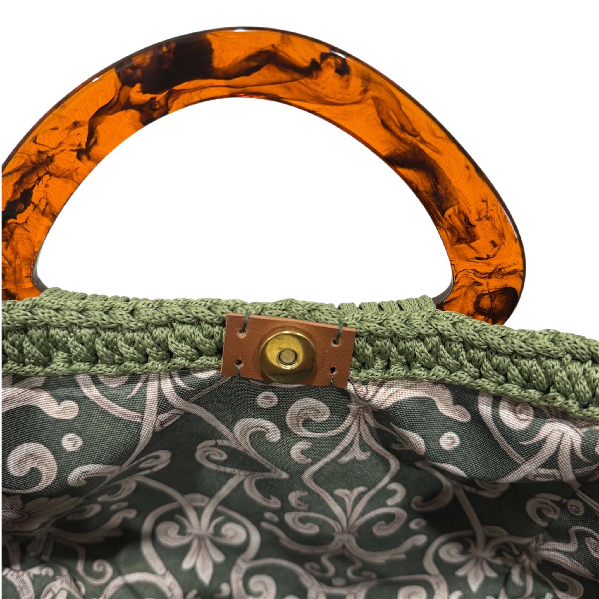 Interior of olive green Paloma handbag with deep green ornamental patterned lining and magnetic closure.