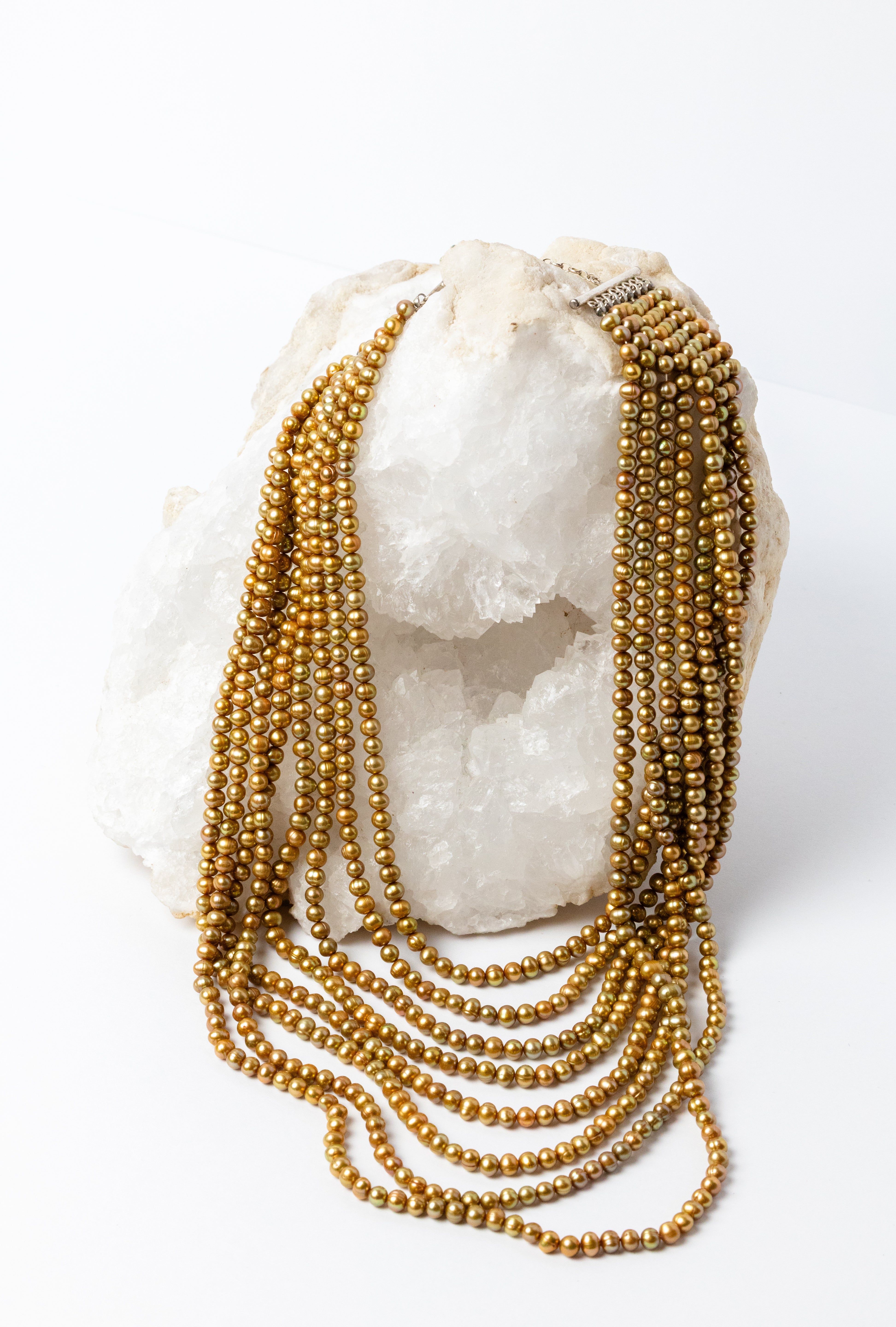 Pearl Opulence Necklace featuring eight cascading strands of natural honey-gold freshwater potato pearls, approximately 6–7 mm, with subtle green undertones and graduated lengths from 18 to 47 inches, plus a 2-inch extension.
