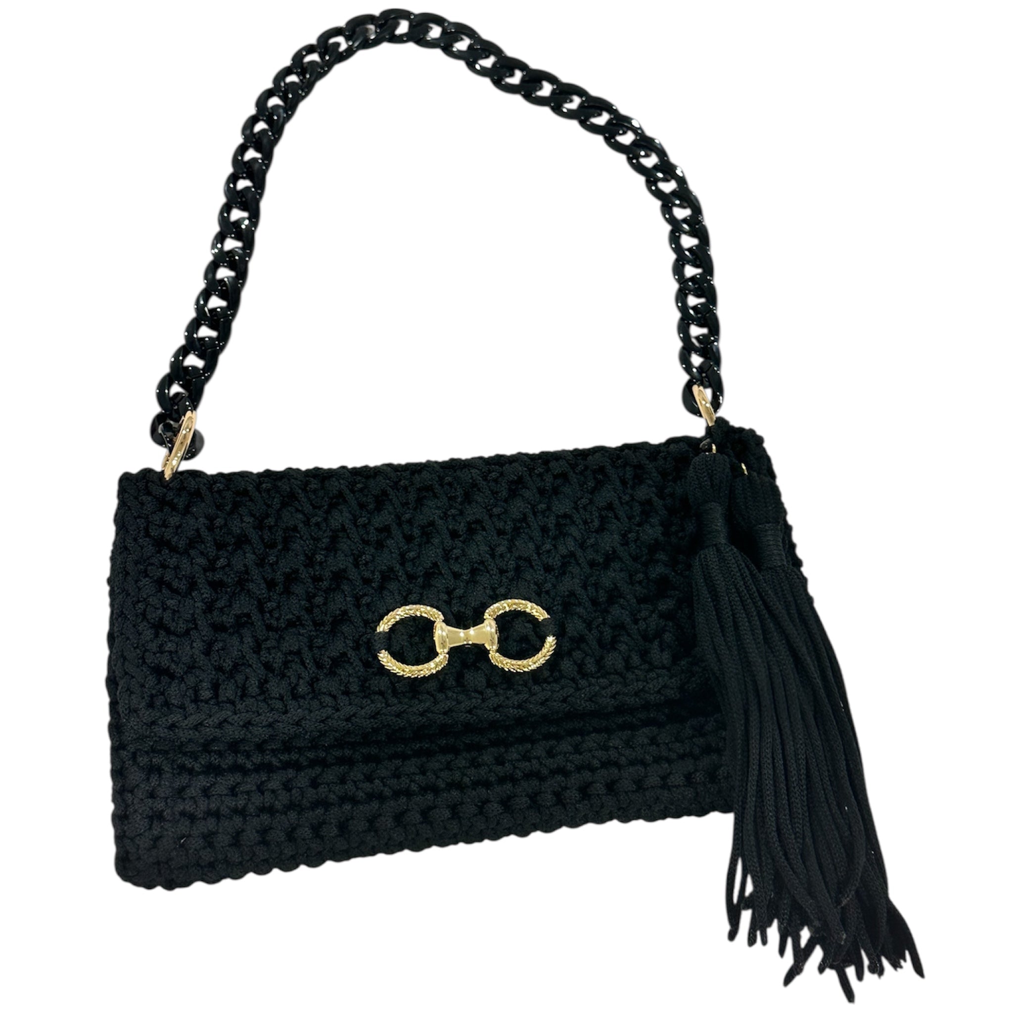 Black hand-crocheted Polly Clutch Ebony Edition featuring a decorative gold-tone front accent, resin chain strap, elegant tassel, and textured crochet finish.