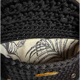 nterior of the Polly Clutch Ebony Edition featuring a botanical lining, decorative gold-tone front accent, magnetic closure, and handcrafted crochet construction.