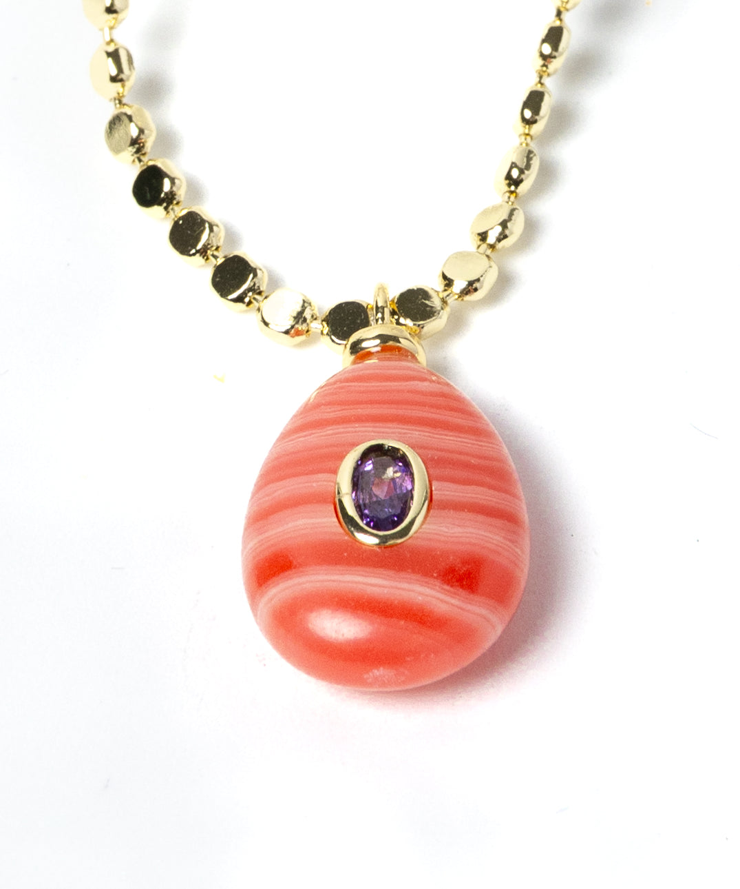 Detailed view of a genuine rhodochrosite pendant featuring distinctive coral-pink striations, a cubic zirconia accent, and gold-plated craftsmanship on an elegant gemstone necklace.