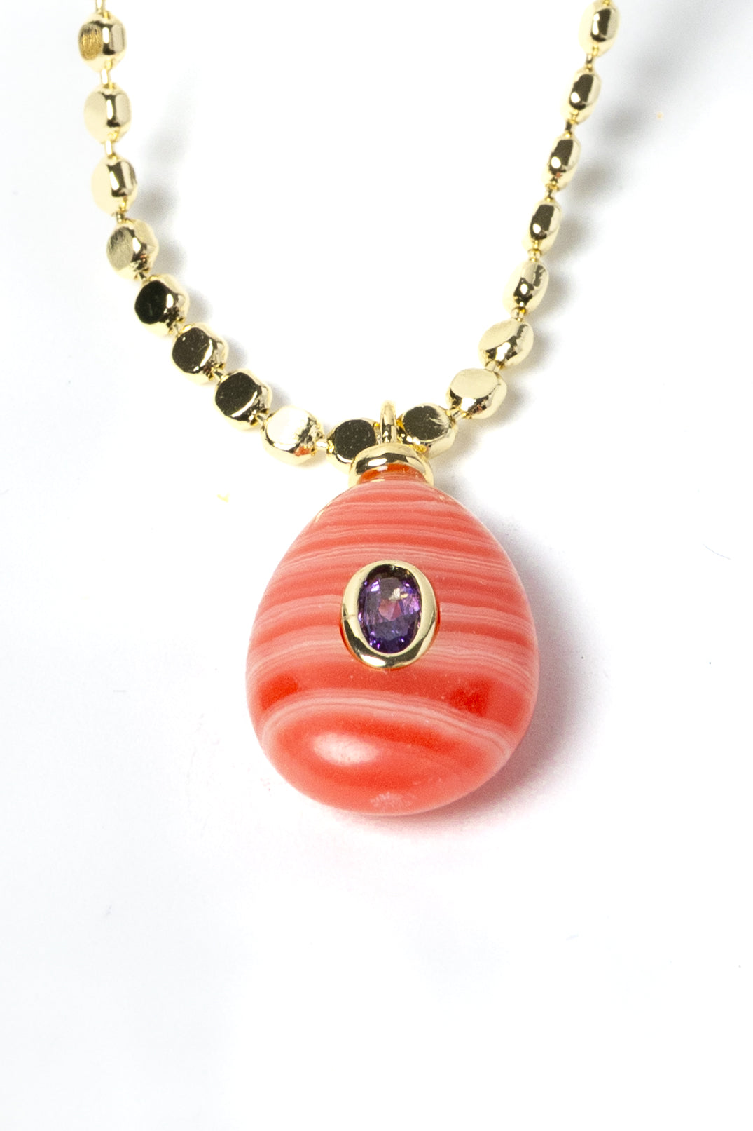 Detailed view of a genuine rhodochrosite pendant featuring distinctive coral-pink striations, a cubic zirconia accent, and gold-plated craftsmanship on an elegant gemstone necklace.