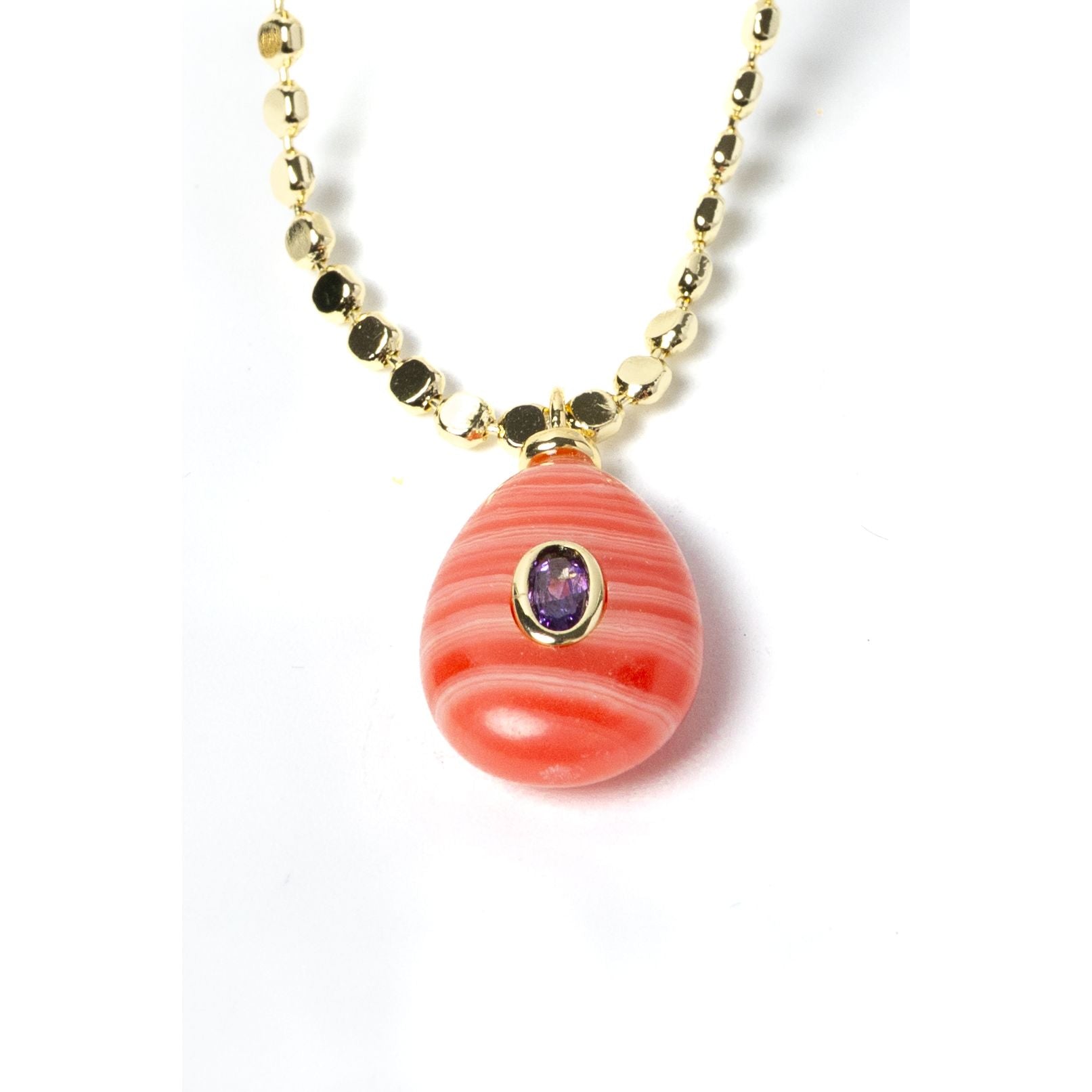 Detailed view of a genuine rhodochrosite pendant featuring distinctive coral-pink striations, a cubic zirconia accent, and gold-plated craftsmanship on an elegant gemstone necklace.