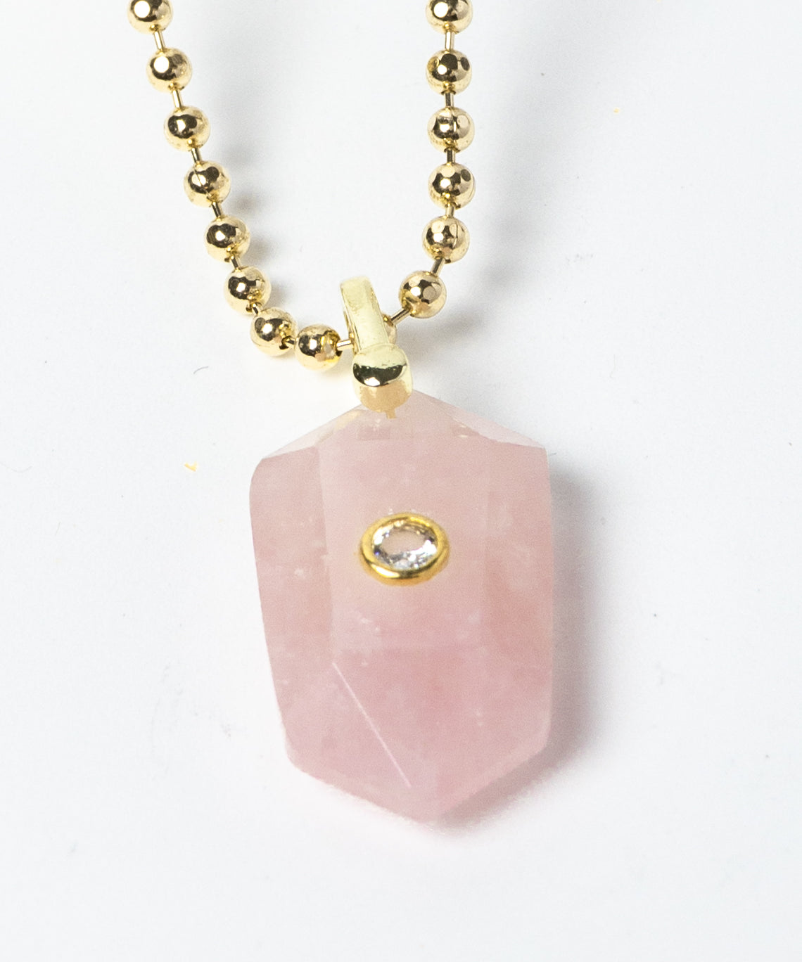 Close-up of a natural Rose Quartz pendant showcasing soft blush-pink tones, faceted geometric shape, cubic zirconia detail, and gold-plated setting.