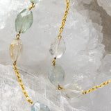 Close-up of Serenity Mist highlighting natural faceted aquamarine gemstones with delicate variations of soft blue and subtle blush tones set along a gold-plated chain.