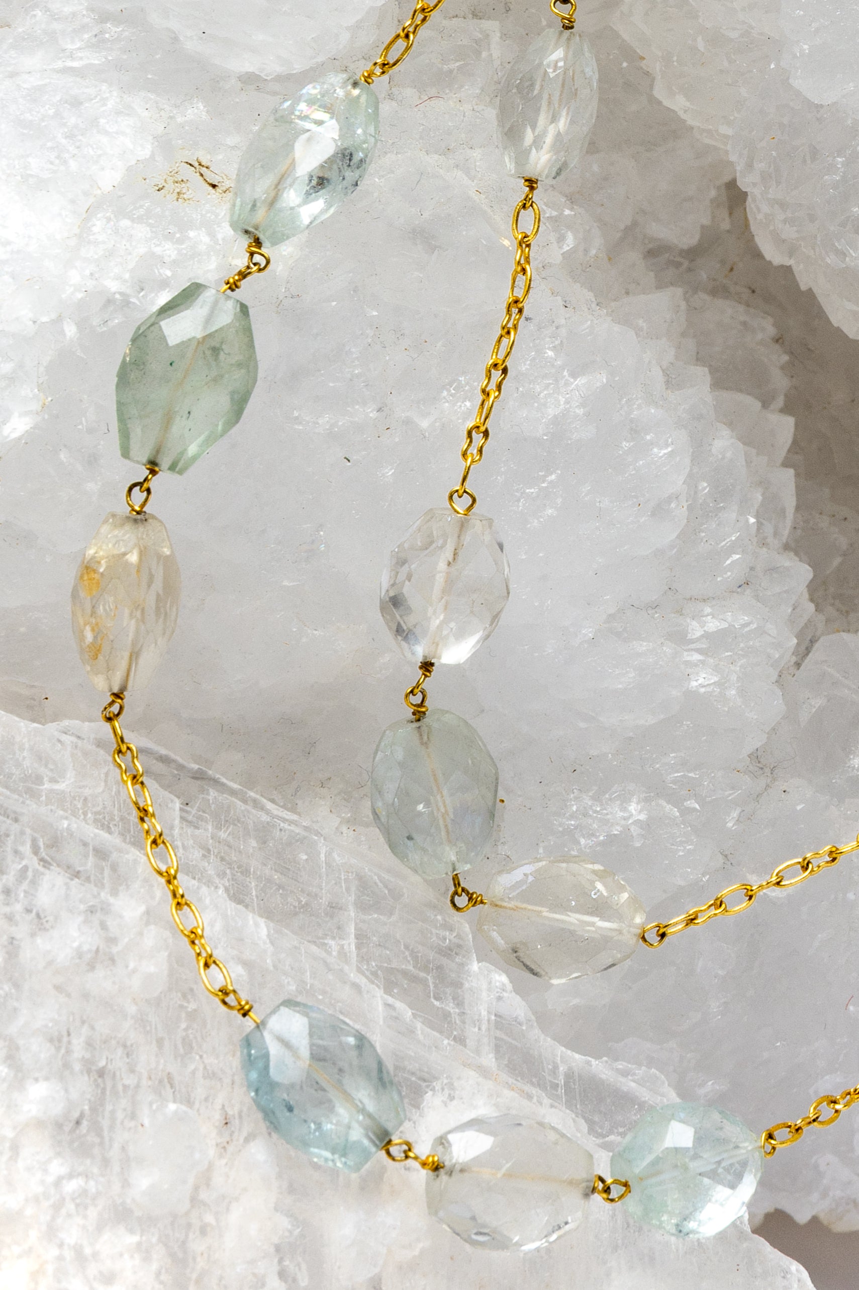 Close-up of Serenity Mist highlighting natural faceted aquamarine gemstones with delicate variations of soft blue and subtle blush tones set along a gold-plated chain.