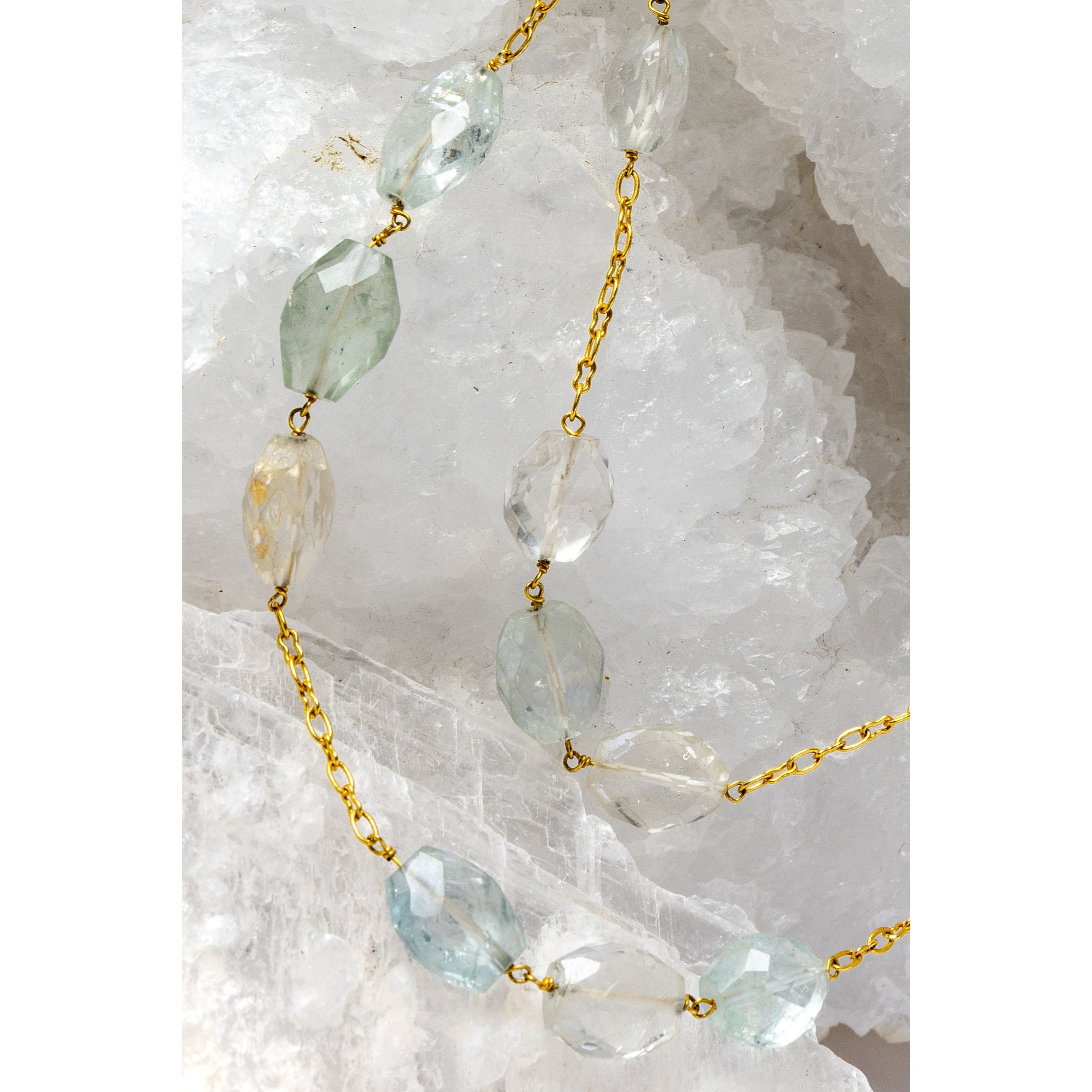 Close-up of Serenity Mist highlighting natural faceted aquamarine gemstones with delicate variations of soft blue and subtle blush tones set along a gold-plated chain.