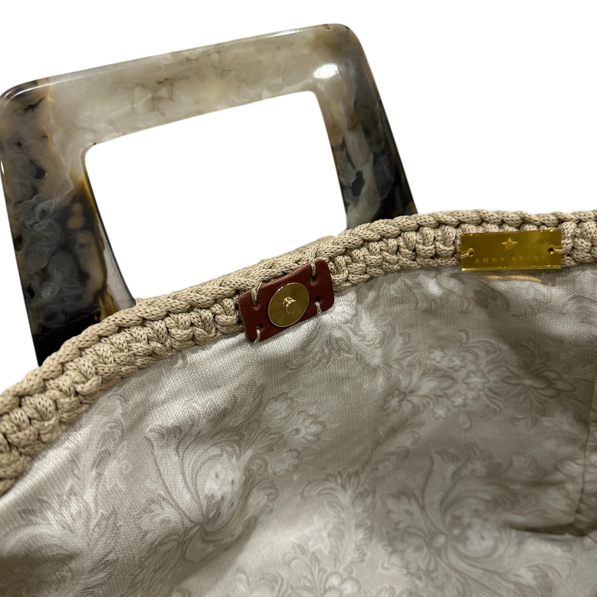 Interior view of the Paloma handbag · Stone Bloom, showing a floral-patterned lining in soft neutral tones, framed by the structured crochet body and finished with refined resin handle details.