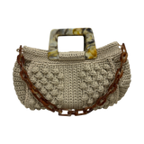 Hand-crocheted Paloma handbag in a soft stone-toned neutral with refined textured stitching, featuring a marbled resin top handle and a coordinating chain strap.