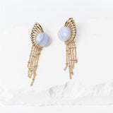Sunburst earrings with 15 mm round natural blue lace agate cabochons, sculptural gold-plated rays, and delicate cascading chains.