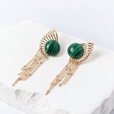 Sunburst earrings with 15 mm round natural malachite cabochons, sculptural gold-plated rays, and delicate cascading chains.