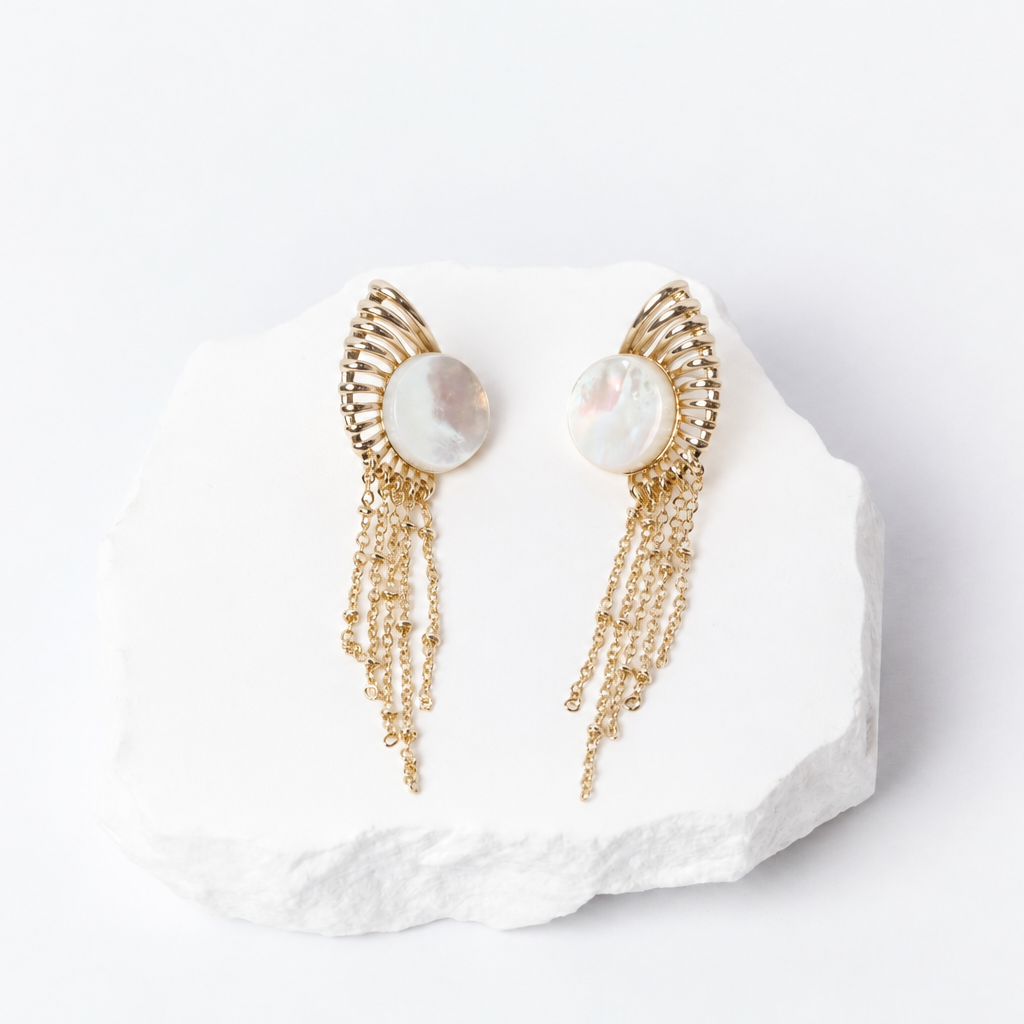 Sunburst earrings with 15 mm round natural mother-of-pearl cabochons, sculptural gold-plated rays, and delicate cascading chains.