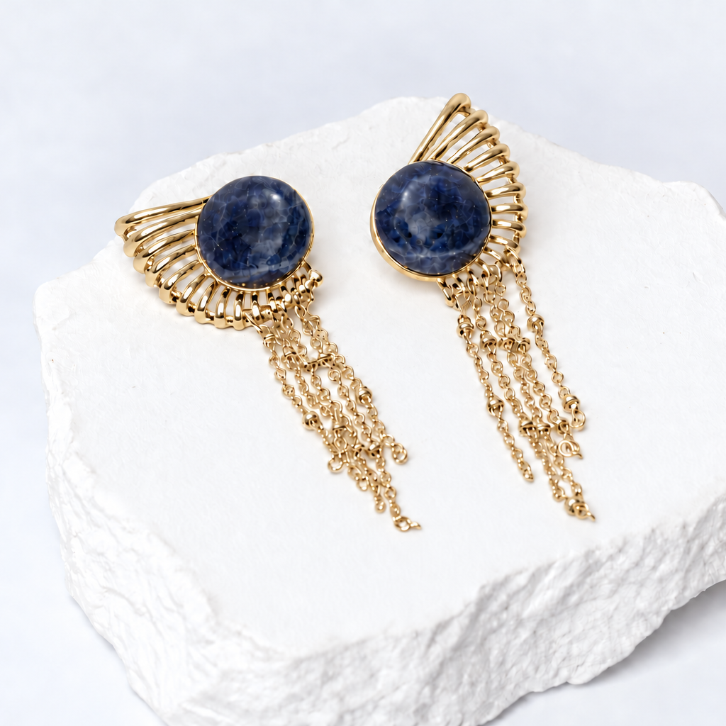 Sunburst earrings with 15 mm round natural sodalite cabochons, sculptural gold-plated rays, and delicate cascading chains.
