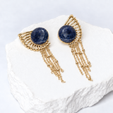 Sunburst earrings with 15 mm round natural sodalite cabochons, sculptural gold-plated rays, and delicate cascading chains.
