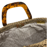 Interior view of the Monique handbag revealing an elegant patterned lining, framed by the textured golden sand crochet structure and finished with refined resin handle details.