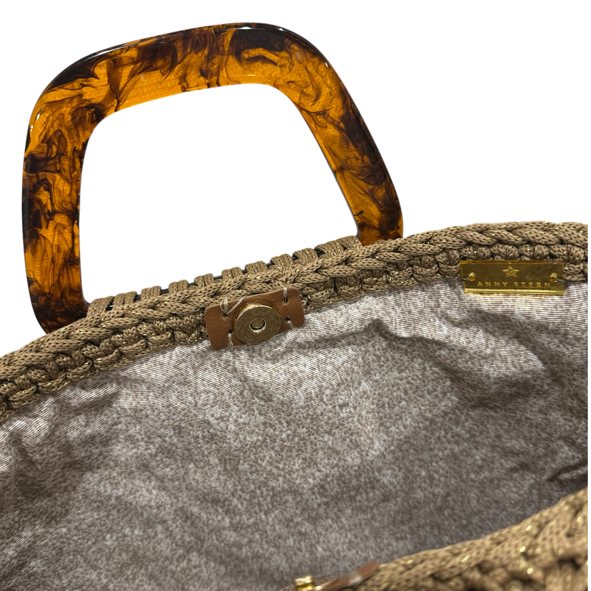 Interior view of the Monique handbag revealing an elegant patterned lining, framed by the textured golden sand crochet structure and finished with refined resin handle details.
