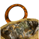 Hand-crocheted luxury handbag interior with botanical lining and spacious open design, featuring dimensional crochet texture, sculptural resin handle and refined chain detail