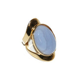 Allure statement ring featuring a natural 25 × 18 mm Blue Lace Agate cabochon with delicate shades of powder blue, soft gray, and creamy white in a sculptural gold-plated setting, ergonomically designed for exceptional comfort.